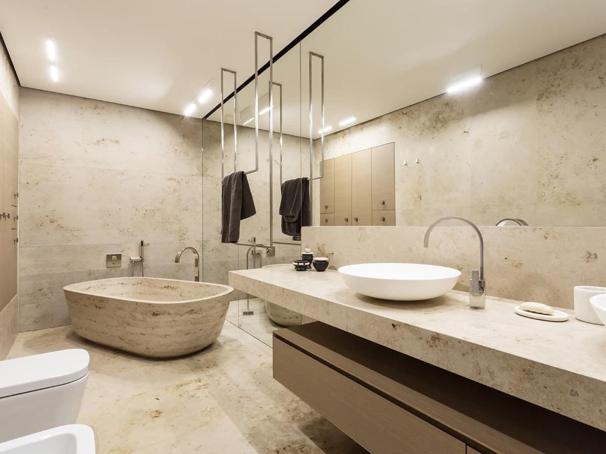 Travertine bathroom with stone freestanding bathtub and vessel sink vanity